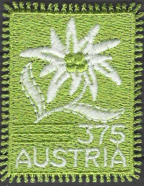 pašto ženklas, Austrija. Gelė edelveisas. Siuvinėtas siūlais ant atlasinio audinio. Gaminamas individualiai. Su kutosais vietoj perforacijos
